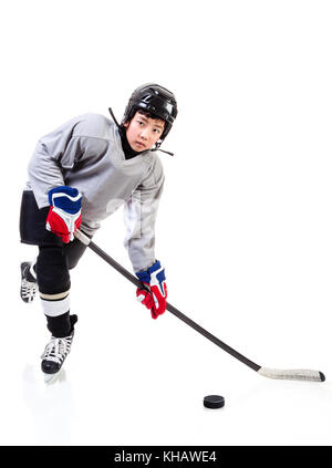 Junior Eishockey Spieler mit voller Ausrüstung und einheitliche für einen Schuß mit einem Puck posieren. auf weißem Hintergrund. Stockfoto