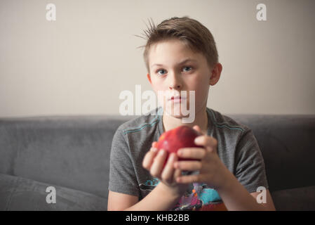 Teenage kaukasischen Jungen mit roten Apfel. Porträt zu Hause. Stockfoto