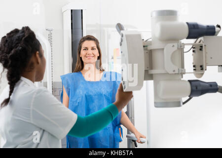 Junge weibliche Radiologe x-ray Maschine auf Patienten im Untersuchungsraum Stockfoto
