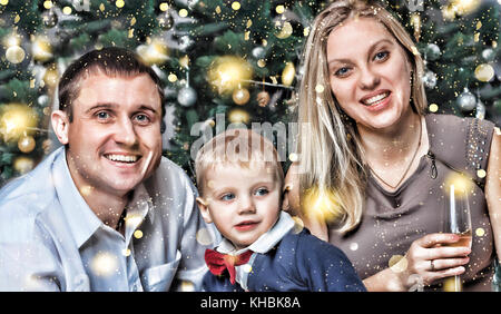 Glückliche junge Familie mit einem kleinen Sohn glücklich lächelnd erfüllt das neue Jahr zu Hause. Weihnachtsbaum, Dekorationen und Geschenke. Neues Jahr Weihnachten. Stockfoto