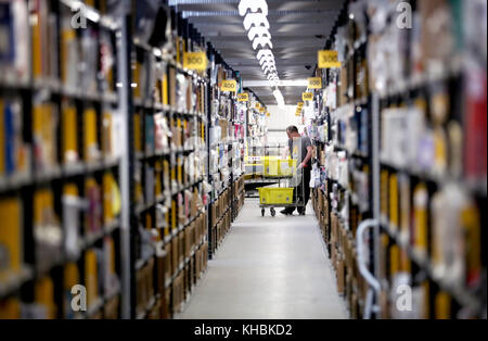 Die Mitarbeiter machen sich auf den Weg durch die Gänge und sammeln Gegenstände, bevor sie sie in die Versandhalle vor Ort schicken, wo sie in einem der größten britischen Amazon-Lagerhäuser in Dunfermline, Fife, verpackt werden. Der Online-Shopping-Riese bereitet sich auf den Weihnachtsrausch und die bevorstehenden Black Friday-Verkäufe vor. Stockfoto