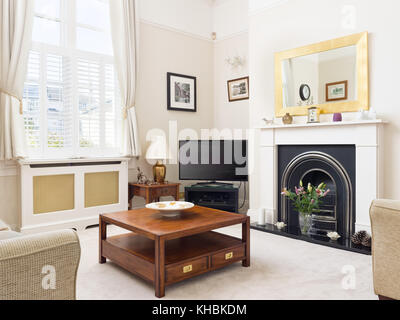 Eine frische, leichte, traditionelle und zugleich moderne Wohnzimmer mit Kamin und Sofas, Couchtisch, Spiegel und einem Fernseher ausgestattet. Stockfoto