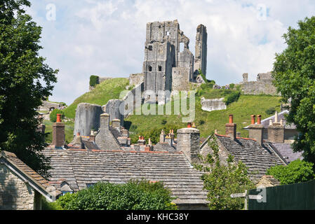 Ein Blick über die alten Dächer der Hütten im Dorf von Corfe Castle in Devon mit der Burgruine mit Blick von oben über ihnen. Stockfoto