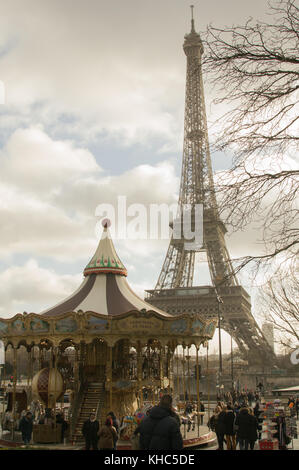 PARIS, FRANKREICH - JANUAR 2016: Ein Mensch schaut auf den Eiffelturm, während andere um ein Karussell in der Nähe des Trocadero-Platzes laufen. Stockfoto