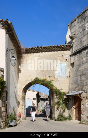 Ein paar Touristen mittleren Alters gehen durch die Porte de la Grande Rue, Stadttor oder Gateway, Grignan, Drome, Drôme Provençale, Provence, Frankreich Stockfoto