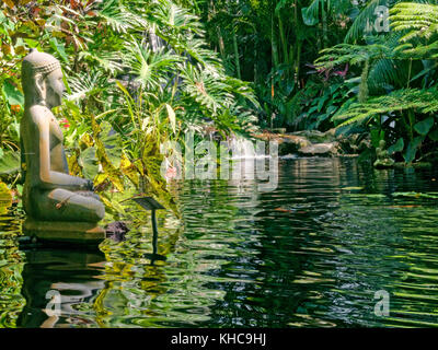 Bronzeskulptur von Gautama Buddha, der in Meditation über einen kleinen Teich blickt. Stockfoto