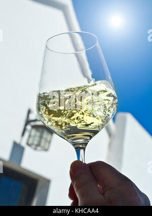 Weißwein Sonne, Glas wirbeln Verkostung und Bewertung in sonnigen blauen Himmel im Freien draußen Wein trinken Probe Terrasse Situation Stockfoto