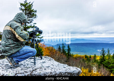 Stehende junge Mann Fotograf mit der Kamera und Stativ an kalten Herbst morgen in Jacke tragen, Felsen, West Virginia, die Bilder von Sunrise Stockfoto