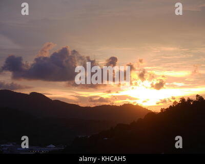 Sonnenuntergang hinter dem Berg gibt es einen schönen Abend Sonnenlicht bewölkter Himmel, schauen Sie aus der Sicht auf dem Berg in der Innenstadt. Stockfoto