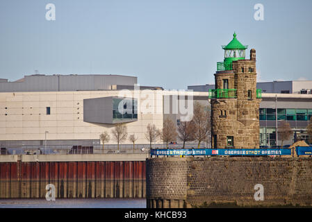 Bremen, Deutschland - November 6., 2017 - Feld Stein Leuchtturm auf einem Stein Kai an der Hafeneinfahrt mit dem Waterfront Einkaufszentrum in der backgrou Stockfoto