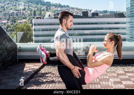 Junge attraktive Paare tun Erweiterte double dare Knirschen beim Stehen auf dem Dach des Gebäudes im städtischen Bereich. Stockfoto