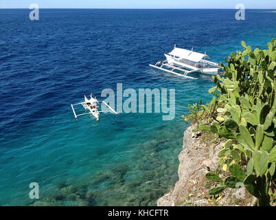 Weiß Outrigger und kleineren Boot durch das Wasser im Leerlauf Stockfoto