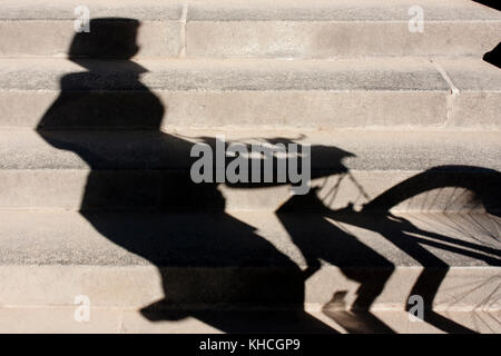 Verschwommene Schatten von einem Radfahrer mit Helm auf und schob sein Rad der öffentlichen Stadt Treppe Stockfoto