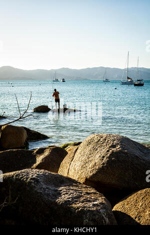 Mann angeln auf einem Felsen an der felsigen Küste in Jurere Beach. Florianopolis, Santa Catarina, Brasilien. Stockfoto