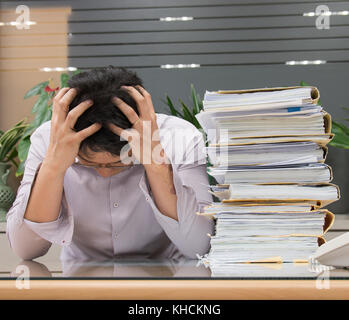 Frustrierte junge Unternehmer seinen Kopf Holding im Büro Stockfoto