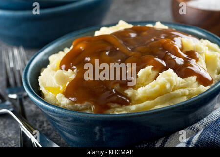 Eine Schüssel leckere Kartoffelpüree mit Sauce und zerlassener Butter. Stockfoto