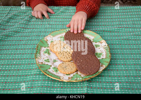 Junge an der Tabelle Auswahl schokoladenbiskuit von Platte, 7/8-Detail Stockfoto