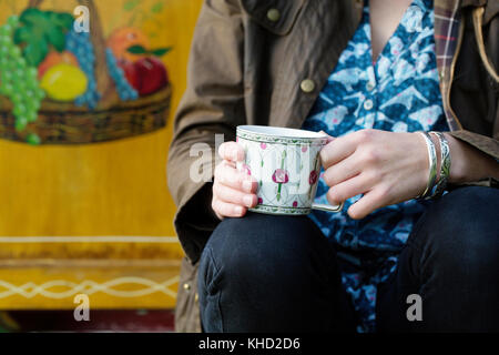 Frau sitzt auf der traditionellen Gypsy Caravan holding Teetasse, mittleren Abschnitt Nahaufnahme Stockfoto