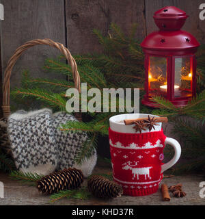Weihnachten Handarbeit gestrickte Becher mit Tee, rote Laterne und ligntning Wolle Handschuhe im rustikalen Hintergrund Stockfoto