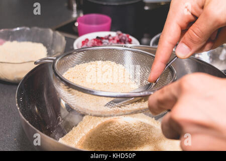 Koch Mixe und Siebe Mandel- Pulver in Mehl in die makronen Rezept Stockfoto