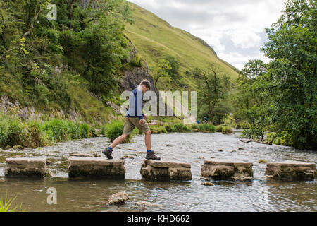 Junge springen über die trittsteine in dovedale Stockfoto