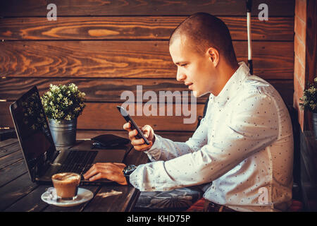 Selbständige glücklicher Mann arbeiten mit einem Laptop und einem Smart Phone im Cafe Stockfoto