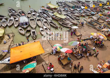 Varanasi ghat Luftaufnahme von bunten Boote aus Holz aufgereiht am Ganges ghat mit Touristen und Anbietern. Stockfoto