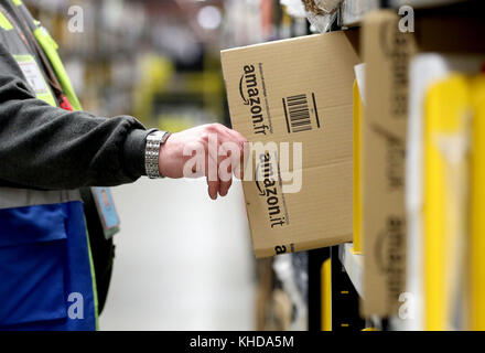 Die Mitarbeiter machen sich auf den Weg durch die Gänge und sammeln Gegenstände, bevor sie sie in die Versandhalle vor Ort schicken, wo sie in einem der größten britischen Amazon-Lagerhäuser in Dunfermline, Fife, verpackt werden. Der Online-Shopping-Riese bereitet sich auf den Weihnachtsrausch und die bevorstehenden Black Friday-Verkäufe vor. Stockfoto