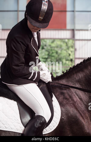 Schöne Mädchen Jockey sitzen im Sattel auf einem Pferd schießen. Ein pedigree Pferd für den Pferdesport. Stockfoto