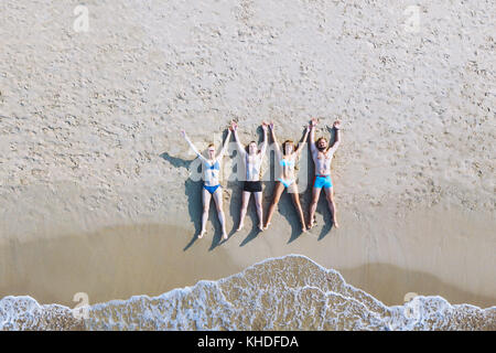 Eine Gruppe von Freunden, die am Strand liegen, tropische Ferien auf dem Meer, Ansicht von oben von drohne von glücklichen Menschen genießen Sommer Reisen Stockfoto