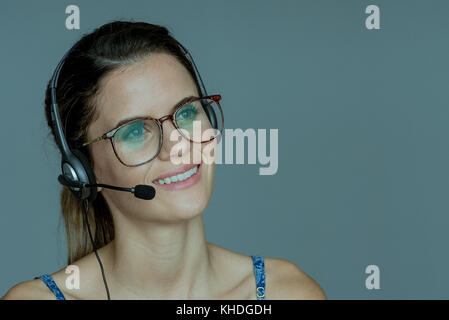 Junge Frau mit Headset, fröhlich lächelnd Stockfoto