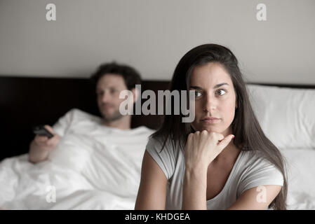 Frau sitzt im Bett, während Ehemann Fernsehen Stockfoto