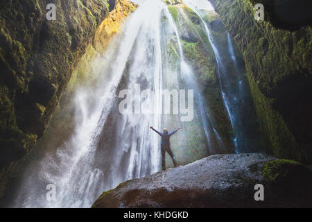 Reisen nach Island, Person mit erhobenen Händen stehen in Wasserfall Gljufrabui, inspirierte Happy Traveler Natur genießen, Abenteuer Konzept Stockfoto