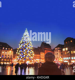christmas market in Europe, decorated xmas tree on the street of city, woman in warm hat enjoying cozy atmosphere Stockfoto
