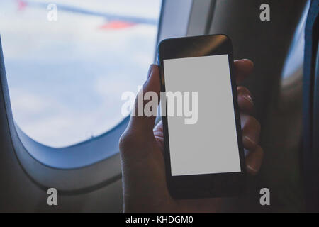 Hand smartphone Holding in Flugzeug, über Handy mit Leeren leeren Bildschirm in der Ebene Stockfoto