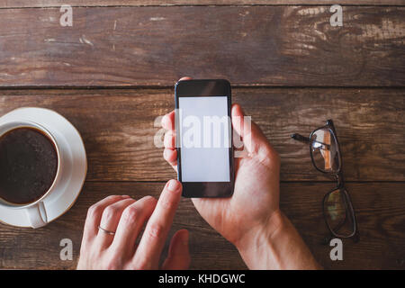 Hand, smart phone mit Leeren leeren Bildschirm auf Holz- Hintergrund Stockfoto