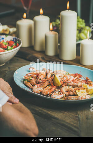 Salat, Garnelen und Kerzen auf hölzernen Tisch Stockfoto