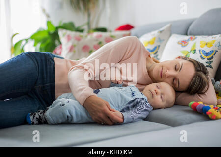 Cute Baby Jungen und seiner Mutter, der lag auf der Couch im Wohnzimmer, schlief friedlich am Nachmittag Stockfoto