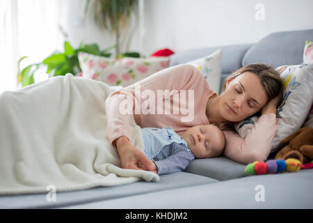Cute Baby Jungen und seiner Mutter, der lag auf der Couch im Wohnzimmer, schlief friedlich am Nachmittag Stockfoto