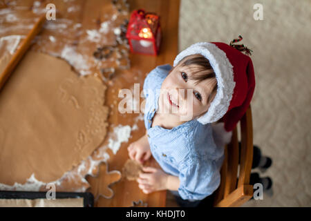 Entzückende kleine Junge Vorbereitungen Cookies für Weihnachten zu Hause, Blick von oben Stockfoto