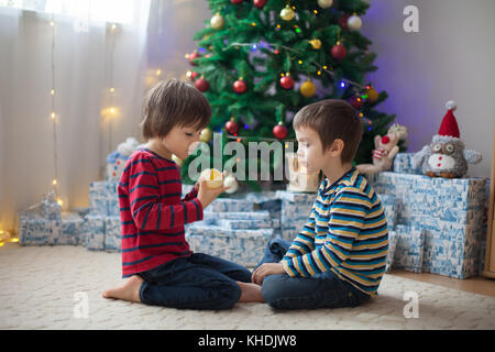 Zwei süße Kinder, junge Brüder, Geschenke auszupacken am Weihnachtstag. Kinder Glück Stockfoto