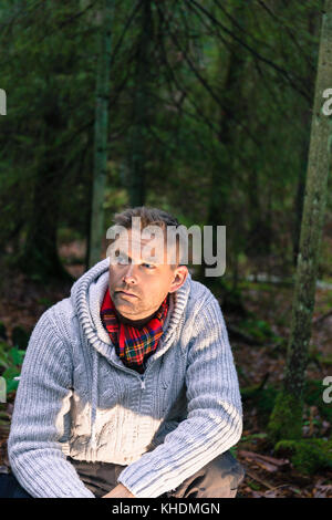 Mitte der erwachsenen Mann in Wäldern lifestyle Portrait tragen gestrickte Pullover und roten Schal weg schauen Model Release: Ja. Property Release: Nein. Stockfoto