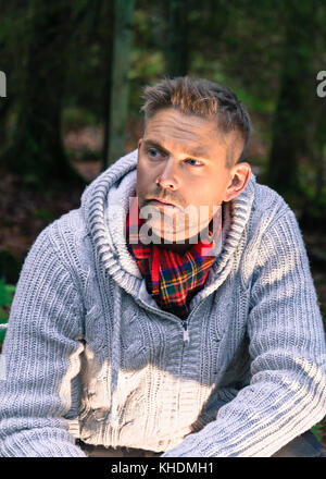 Mitte der erwachsenen Mann in Wäldern lifestyle Portrait tragen gestrickte Pullover und roten Schal weg schauen Model Release: Ja. Property Release: Nein. Stockfoto