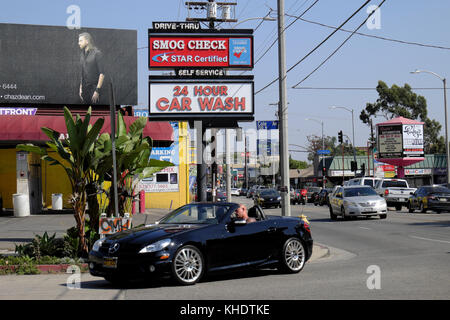 Cabrio Auto und Verkehr auf der Melrose Avenue in der Nähe von Cole Ave und Smog prüfen 24 Stunden Auto waschen sign Hollywood, Los Angeles, Kalifornien USA KATHY DEWITT Stockfoto