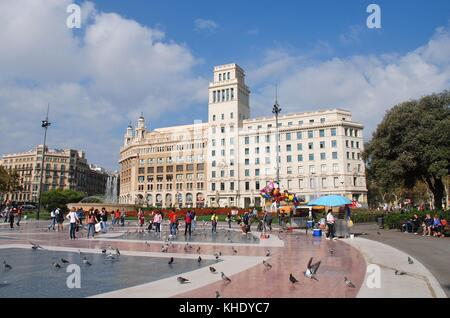 Menschen gehen in der Placa de Catalunya in Barcelona, Spanien am 1. November 2017. Der Flagship Store von Kleidung Marke Desigual ist im Hintergrund. Stockfoto