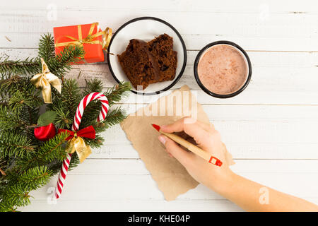 Frau Hand schreiben ein weihnachtsbrief auf weißen Tisch mit Winterurlaub Dekorationen Stockfoto