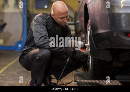 Automechaniker mit Schraubendreher ändern Autoreifen Stockfoto