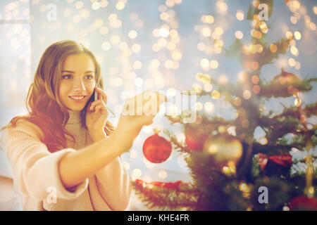 Frau mit Smartphone schmücken Weihnachtsbaum Stockfoto