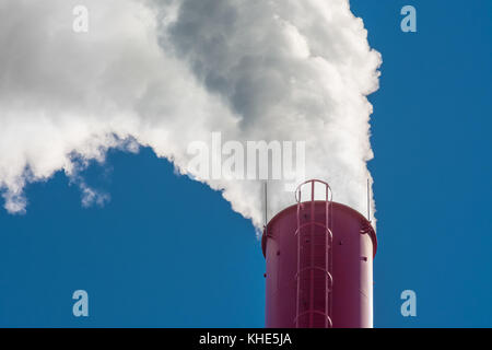 Red industrielle Schornstein. dichten weißen Rauch aufsteigend von hohen factory Schornstein am blauen Himmel. Stockfoto