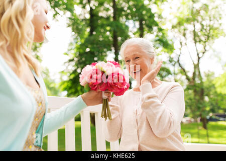 Tochter, die Blumen zu den älteren Mutter im Park Stockfoto